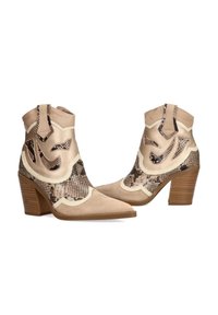Botines beige con tacón ancho, fabricados en material de ante y con acentos de estampado de serpiente. Punta afilada y cortes decorativos a los lados.
