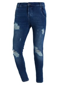 Jeans skinny de denim azul oscuro con desgastes rasgados en las rodillas y un ligero desvanecimiento. Presentan un cierre estándar con botón y cremallera.