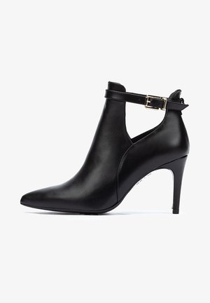 Stivaletto in pelle nera a punta, con alto tacco a stiletto e una cinghia regolabile con fibbia dorata. Texture liscia e design elegante.