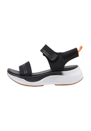 Sandalia deportiva negra con correas de Velcro ajustables, parte superior negra texturizada, media suela blanca y suela de goma con un tirador naranja.