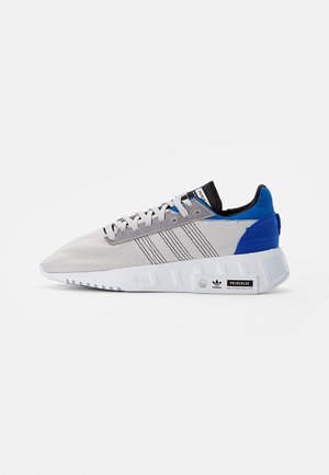 Szaro-niebieski niskoprofilowy but sportowy Adidas z białą podeszwą, trzema czarnymi paskami po bokach oraz etykietą "Primeblue" na śródpodeszwie.