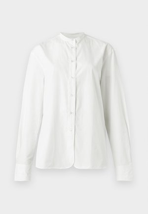 Bijela košulja s dugim rukavima i gumbima, mandarin okovratnikom, glatkom tkaninom i blago zaobljenim rubom, prikazana na jednobojnoj pozadini.