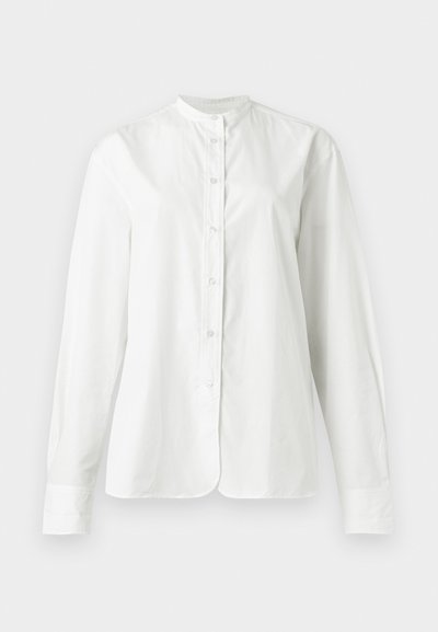 Λευκό πουκάμισο με μακριά μανίκια και κουμπιά, γιακά μανταρίνι, λείο ύφασμα και ελαφρώς στρογγυλεμένο τελείωμα, παρουσιάζεται σε απλό φόντο.