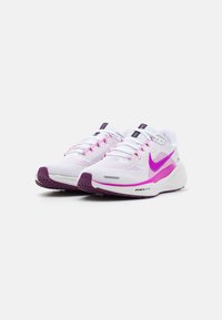 Bijele sportske tenisice s ružičastim detaljima, gornjište od mrežaste tkanine za prozračnost, ljubičasti potplat i Nike logo sa strane i na jeziku.