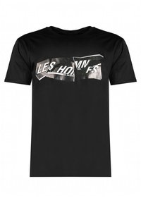 Camiseta de algodón negra con un estampado gráfico desgastado en plata que incluye el texto "LES HOMMES" y "EST. ANTWERP" en la parte frontal.