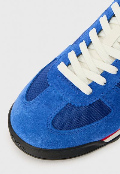 Niebieskie sneakersy z zamszowymi i siateczkowymi materiałami, okrągłymi białymi sznurowadłami, teksturowanym wierzchem oraz subtelnymi czerwonymi i białymi paskami na podeszwie.