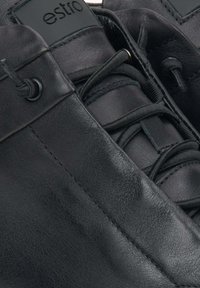 Czarne skórzane buty o gładkiej fakturze, wyraźnym sznurowaniu i metce z logo. Projekt zawiera zaokrąglone krawędzie i subtelne detale w szwie.