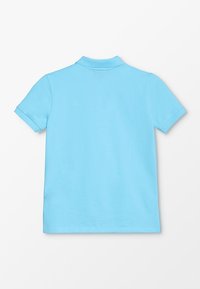 Světle modrá polo košile z bavlny, s krátkými rukávy, límečkem a hladkým povrchem, bez viditelných log nebo vzorů.