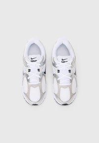 Bílé a šedé tenisky Nike s neoprenovými panely, polstrovaným límcem a tkaničkami. Mají gumovou podrážku a černé logo na jazyku. Zaoblený design špičky.