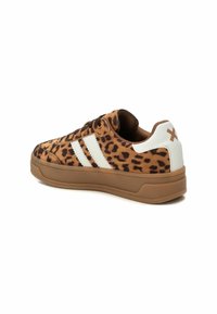 Zapatillas de leopardo con parte superior de ante marrón, rayas blancas y suela de goma marrón. Tacón reforzado y diseño de cordones.
