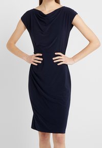 Vestido de marina con mangas cortas, escote drapeado y silueta ajustada. Hecho de una tela suave con un ligero brillo y una textura sutil.