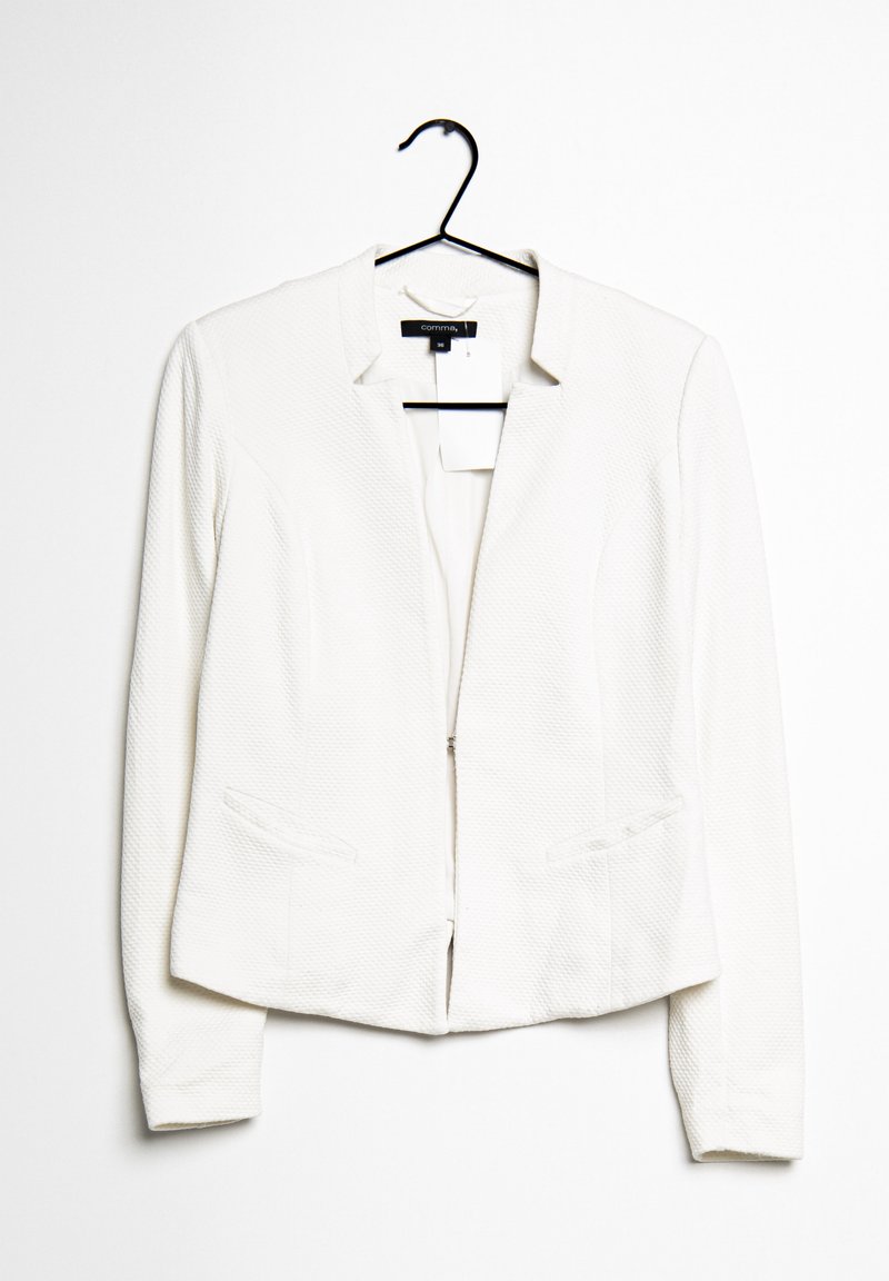 Blazer blanc texturé pour femme avec col à revers et deux poches avant, suspendu sur un cintre noir sur fond blanc.