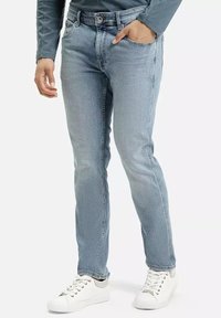 Jasnoniebieskie dżinsy o prostym kroju, z klasycznym pięcio-kieszeniowym wzorem i subtelnymi detalami przeszyć, noszone z białymi sneakersami.