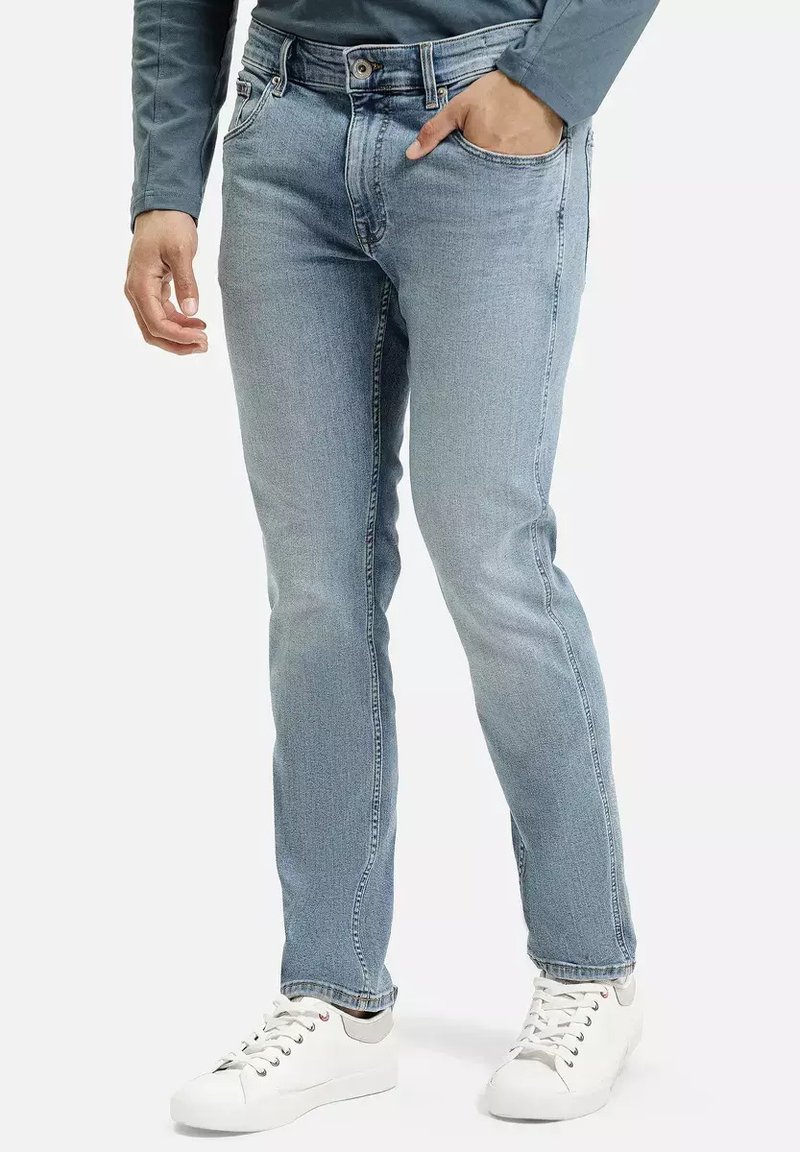 Jasnoniebieskie dżinsy o prostym kroju, z klasycznym pięcio-kieszeniowym wzorem i subtelnymi detalami przeszyć, noszone z białymi sneakersami.