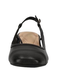 Chaussure à talon noir avec un bout en relief, des côtés lisses et une bride réglable. L'intérieur présente une semelle rembourrée.