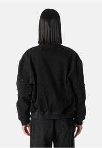 Černá denimová mikina se strukturovanými ozdobnými hroty; oversized střih; žebrované manžety a lem; jednobarevná černá tkanina s matným povrchem.