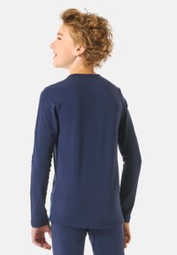 Camicia a maniche lunghe di colore navy realizzata in tessuto morbido, con collo a giro e maniche aderenti. Design minimalista senza motivi o grafiche visibili.