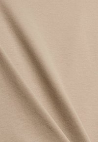 Tessuto di cotone beige con una texture morbida, caratterizzato da una superficie liscia e una leggera lucentezza. Leggera elasticità e caduta con pieghe diagonali.