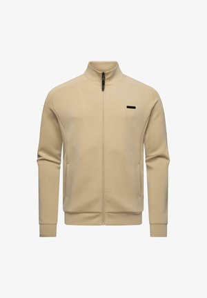 Beżowa kurtka na pełny zamek z wysokim kołnierzem, długimi rękawami, bocznymi kieszeniami i małym czarnym prostokątnym logo na lewej piersi.