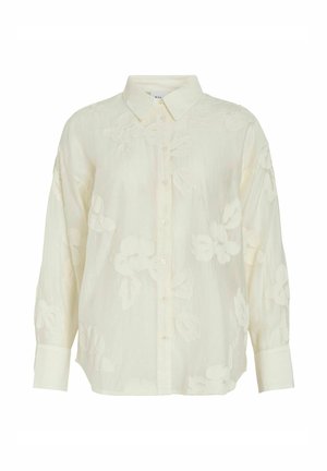 Blouse crème à manches longues avec broderie florale subtile, devant boutonné, col classique et larges poignets.