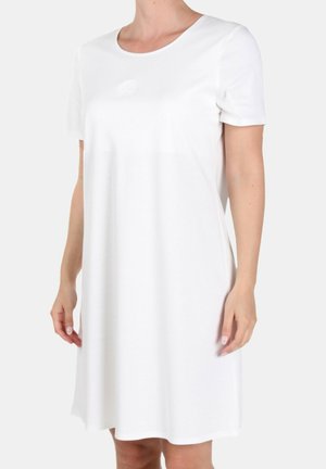 Vrouw draagt een eenvoudige witte jurk met korte mouwen tot op de knie, met een ronde hals en een subtiel reliëflogo op de borst.