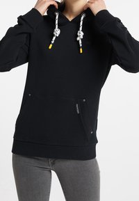 Sweat à capuche noir avec poche frontale, capuche à cordon avec embouts jaunes et tissu texturé. Conçu pour le confort et un look décontracté.