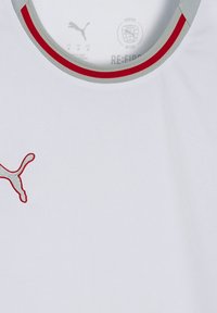 Maglietta sportiva bianca con scollatura rotonda, rifinita con bordi a strisce grigie e rosse, e logo Puma grigio sulla parte sinistra del petto.