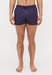 Shorts de bain pour hommes dans un motif ondulé bleu foncé et noir, fabriqués en tissu léger avec une taille élastique et un cordon de serrage.