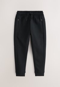 Pantaloni da jogging neri a taglio svasato con vita elastica, coulisse, tasche laterali con cerniera e polsini a coste alle caviglie su sfondo chiaro.