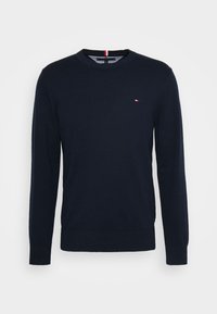 Pull en jersey bleu marine à col rond avec manches longues, confectionné en tissu doux, avec un petit logo brodé en rouge, blanc et bleu sur la poitrine.