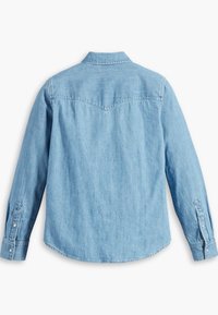 Chemise en denim bleu clair à manches longues, vue de dos, avec des poignets boutonnés et une couture en pointe au niveau des épaules.