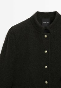 Dark woolen coat with a rounded collar, featuring silver buttons along the front. Soft texture and minimalistic design.