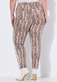 Strak zittende legging in een slangenprintdesign met bruin- en crèmekleuren, voorzien van een hoge tailleband en zijpanelen. Geschikt voor casual wear.