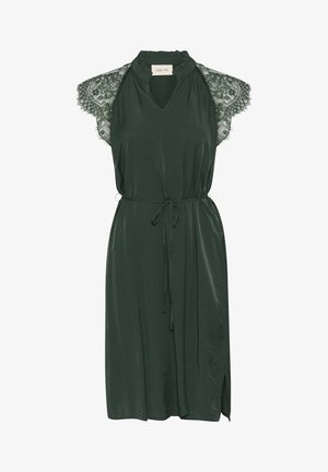 Tumši zaļa kleita ar mežģīņu īsām piedurknēm, atslēgas cauruma dekoltē un jostu viduklī. Izceļas ar brīvu piegriezumu un sānu izgriezumiem papildu kustībai.