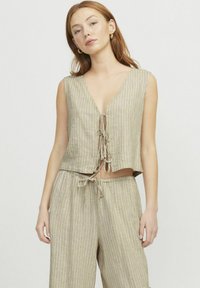 Beige, mély V kivágású cropped top, elöl megkötős részlet. Texturált anyagból készült, függőleges csíkokkal, összepárosítva a hozzá illő nadrággal.