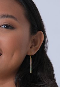 Gul hoopörhänge med en vertikal stav prydd med en gradient av multikolerade rhinstenar. Designen är smal och avlång, passar bra för vardagsbruk.