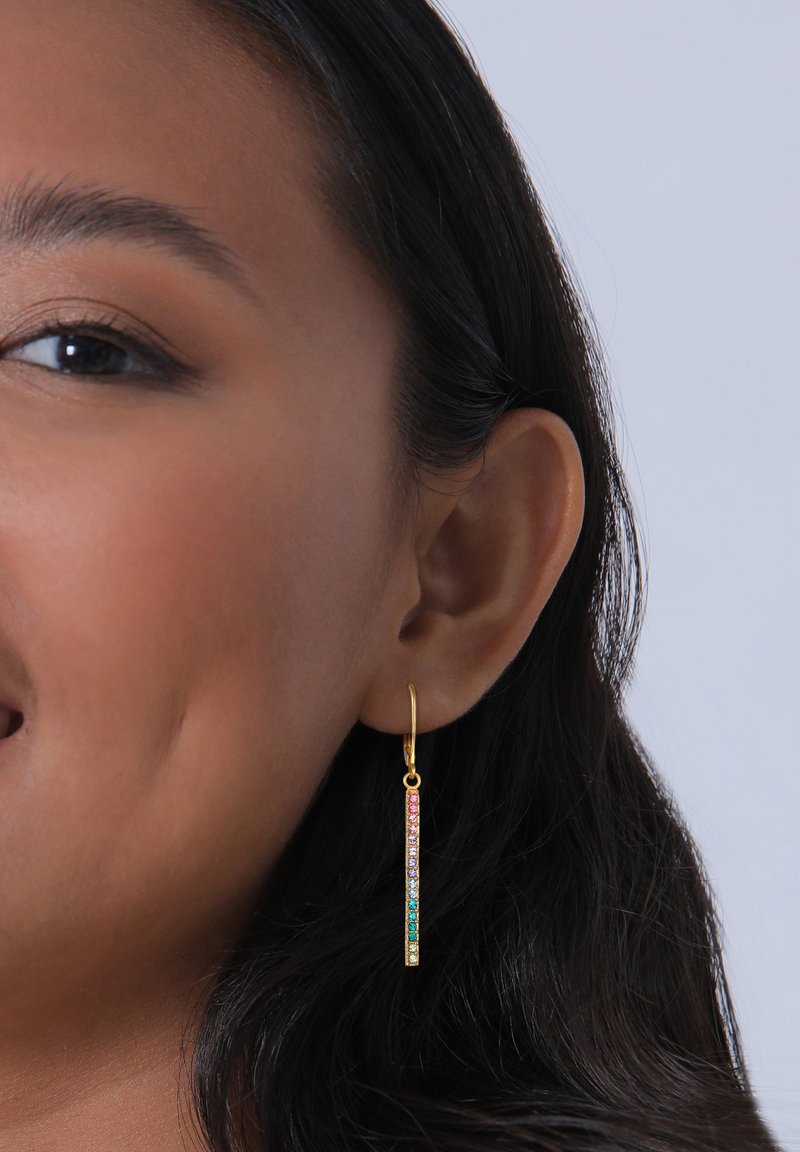 Gul hoopörhänge med en vertikal stav prydd med en gradient av multikolerade rhinstenar. Designen är smal och avlång, passar bra för vardagsbruk.