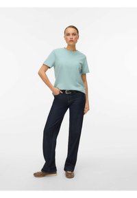 Lyseblå kortærmet skjorte med rund halsudskæring, kombineret med mørkeblå viddeben jeans og brune snørestøvler. Simpelt, afslappet design.