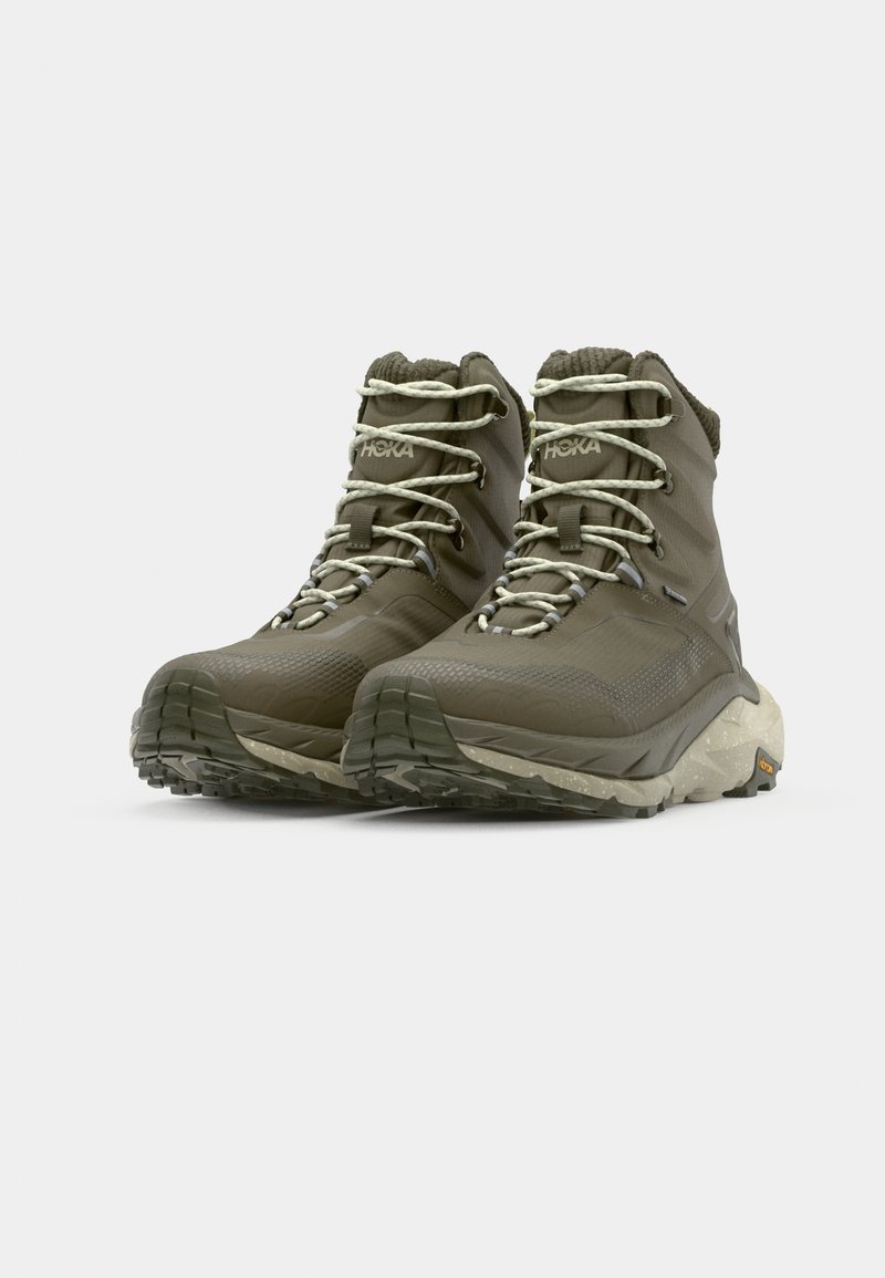 Olijfgroene wandelschoenen met een gestructureerde synthetische bovenkant, een gevoerde kraag en lichtgekleurde veters. Voorzien van een robuuste buitenzool voor grip.