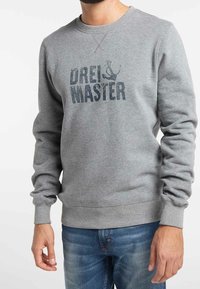 Felpa grigia con polsini e orlo a coste, con la scritta "DREI & MASTER" stampata in lettere blu scuro sulla parte frontale. Tessuto morbido.