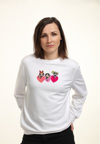 Felpa bianca a maniche lunghe con tre personaggi animati su cuori rosa. Tessuto morbido con scollo rotondo e vestibilità comoda.