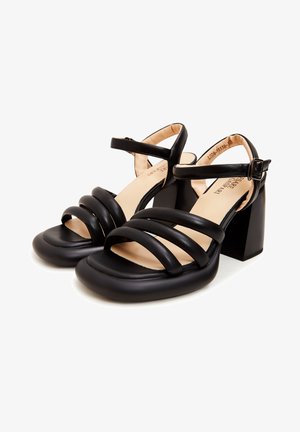 Zwarte sandalen met hakken, voorzien van meerdere gekruiste banden, een vierkante neus en een chunky hak met een gladde textuur en beige binnenvoering.