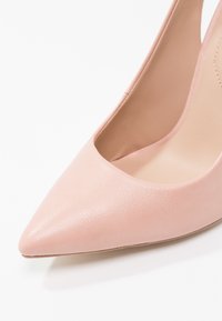 Chaussure à talon haut en cuir rose à bout pointu avec une texture lisse sur fond blanc.