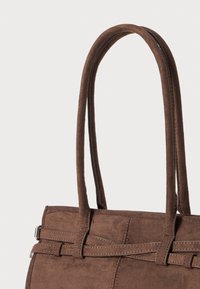 Smeđa mokasinska torba s dva duga, uska ručka. Sadrži šivane detalje i elegantan dizajn, prikazujući mekanu, teksturiranu površinu.