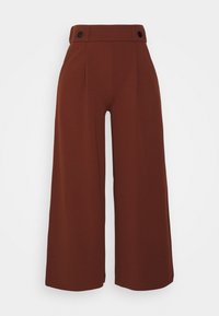 Pantalons évasés en tissu marron, dotés d'une taille plate, de deux boutons noirs à la ceinture et d'une texture lisse.