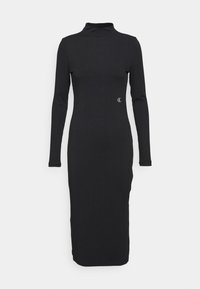 Abito nero a coste con colletto alto finto, maniche lunghe e silhouette aderente. Presenta un piccolo logo sul lato sinistro vicino alla vita.