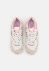 Paire de baskets New Balance 550 blanches et rose clair vues de dessus, montrant les lacets et les colliers de cheville rembourrés.