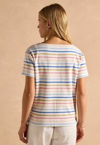 Striped short-sleeve top in white, featuring horizontal stripes in blue, pink, and beige. Soft fabric with a relaxed fit and wide neckline.