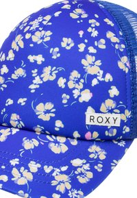 Blå blomstret kasket med netbagside, der har små beige og pink blomster, og et hvidt mærke med "ROXY" broderet på frontskyggen.