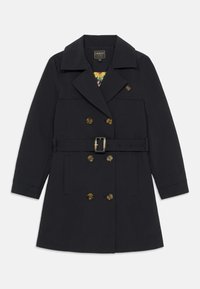 Manteau de marine en tissu résistant, croisé avec des boutons dorés, taille ceinturée et large col. Doublure florale visible.